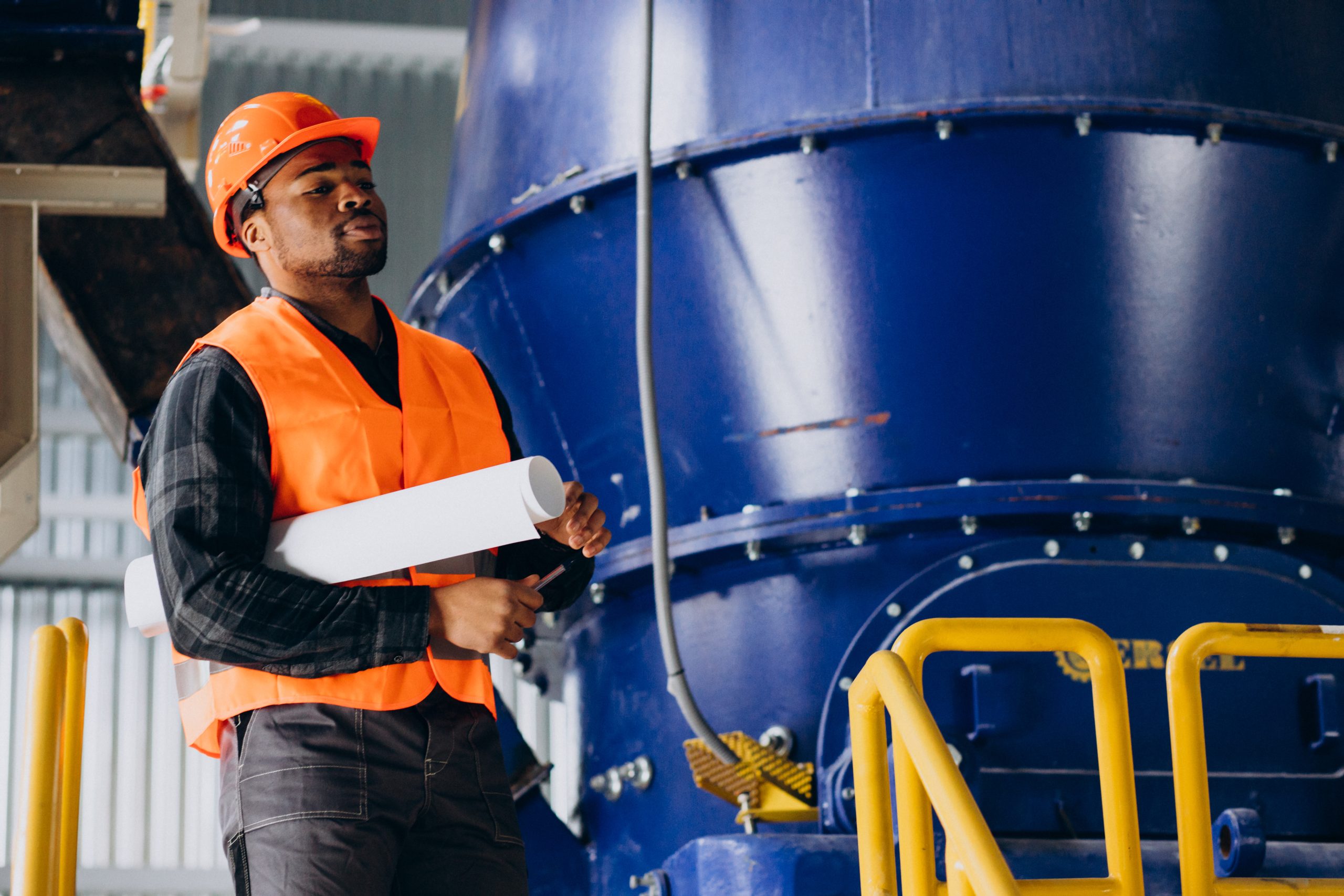 African american worker standing in uniform wearing a safety hat in a factory